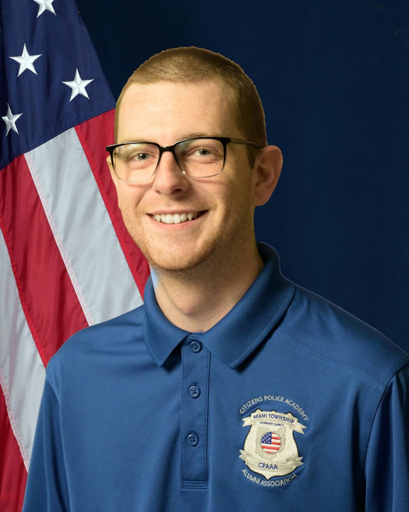 A portrait of Joshua Ferris in front of an American Flag and blue background.